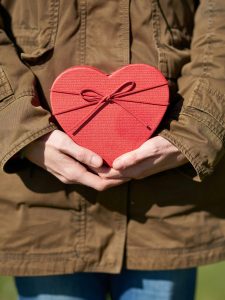 KinseyInvestigations.com Private Investigator with a Heart - A person wearing a jacket holds a heart-shaped box.