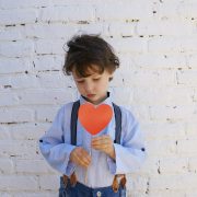 KinseyInvestigations.com Child Custody - A young boy holds a paper heart in front of his chest.