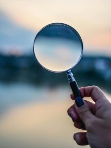 KinseyInvestigations.com Hire a Private Investigator - A magnifying glass is held against a horizon.