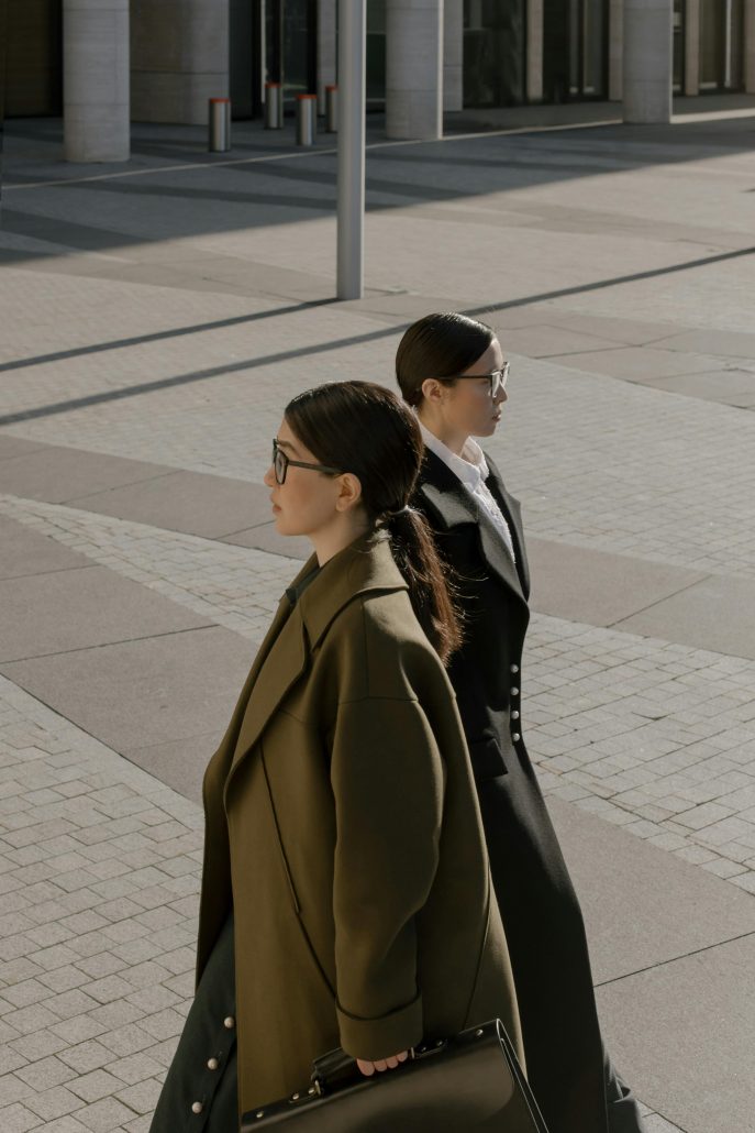 Two women in suits walking past each other in opposite directions - Visit KinseyInvestigations.com. 