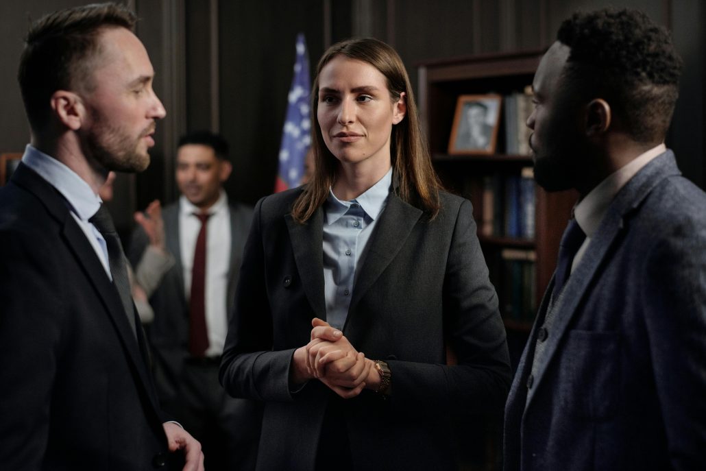 A woman standing in conversation between two men in a courtroom - Visit KinseyInvestigations.com. 