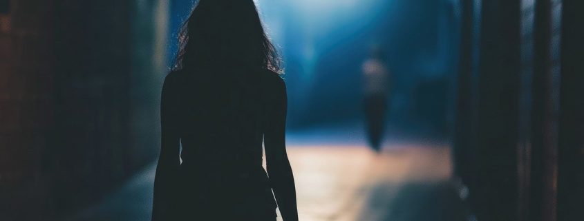 The silhouette of a woman in the dark as someone follows her - visit KinseyInvestigations.com.