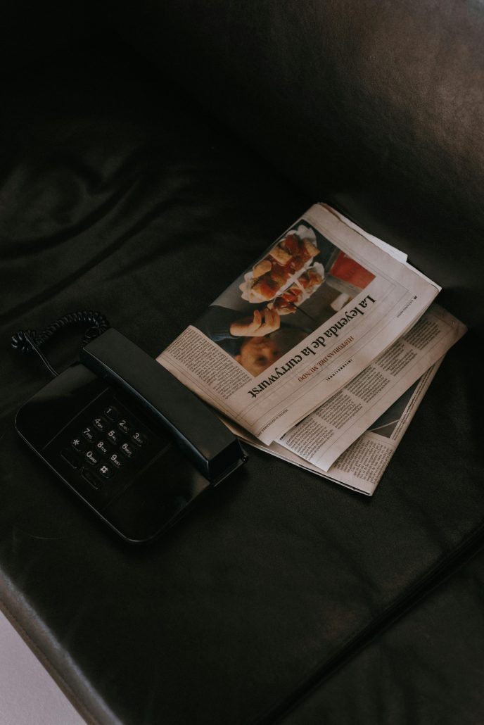 A newspaper on a couch next to a phone - Visit KinseyInvestigations.com.