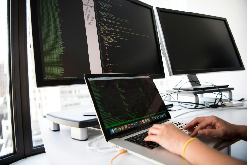 A woman's hands at the keyboard of a laptop seated in front of several other computer screens - Visit KinseyInvestigations.com. 