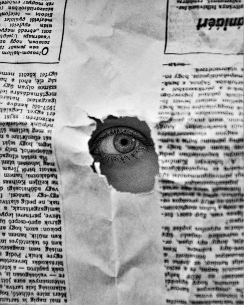 A woman's eye peeking out through a hole in a newspaper - Visit KinseyInvestigations.com. 