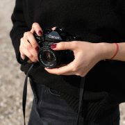 View of female detective from neck to waist holding a camera in her hands - Visit KinseyInvestigations.com.