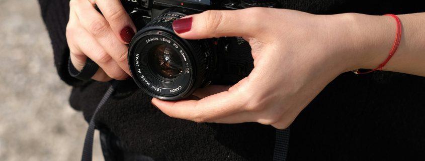 View of female detective from neck to waist holding a camera in her hands - Visit KinseyInvestigations.com.