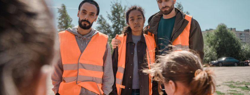 A group of people wearing high-visibility vests. One is looking at a missing persons flyer.