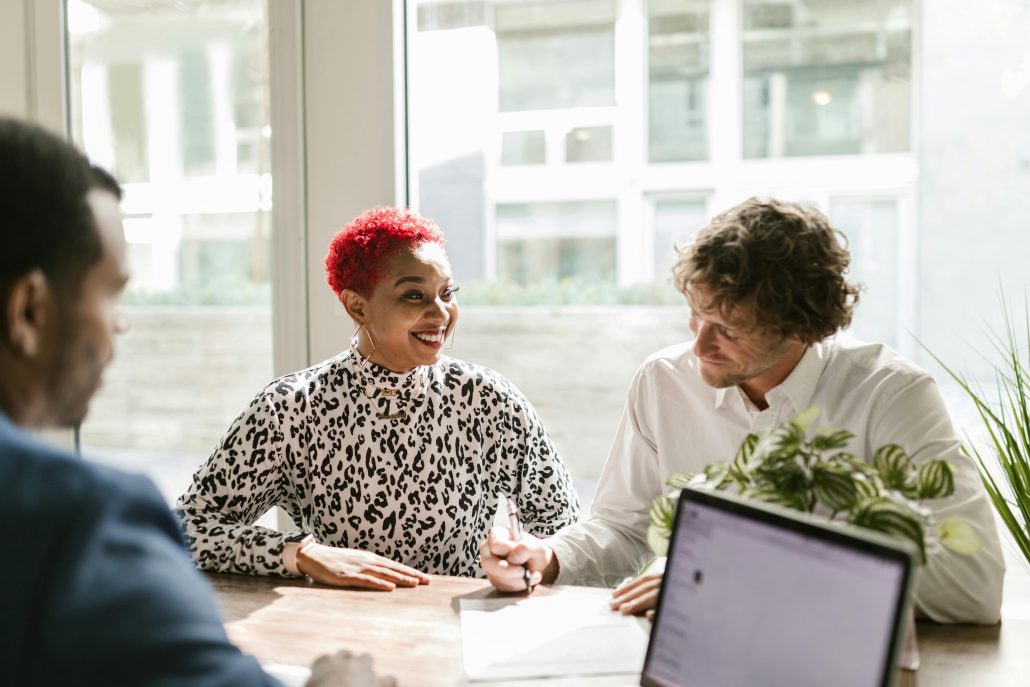 A black woman with red hair sitting beside a white man with curly dark hair as they read some forms - Visit KinseyInvestigations.com.