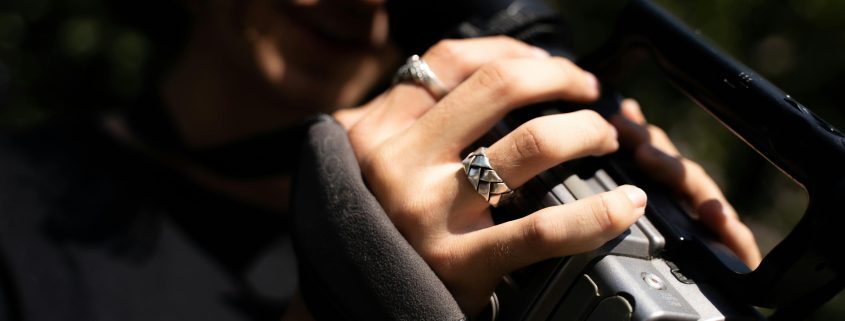 A woman's hands with silver rings holding a recording camera - Consult KinseyInvestigations.com.