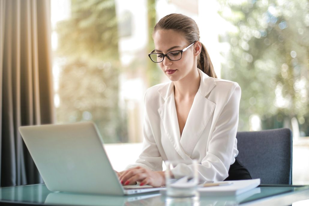 Adult professional woman in a white blouse at a laptop - Consult KinseyInvestigations.com.