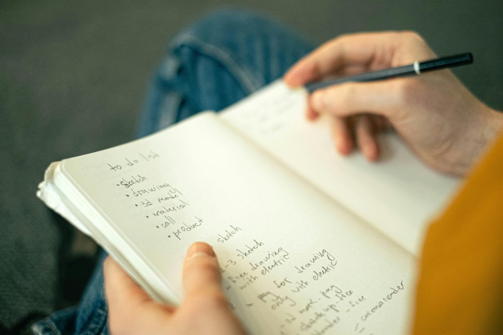 A woman writing in a notebook seen over her shoulder - Consult KinseyInvestigations.com.